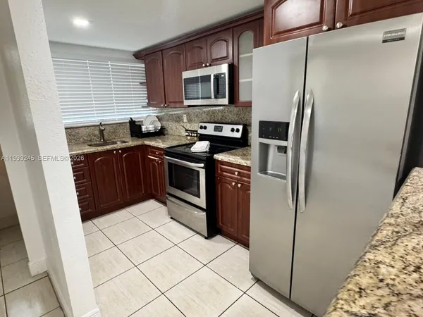 a kitchen with stainless steel appliances granite countertop a refrigerator stove and a sink