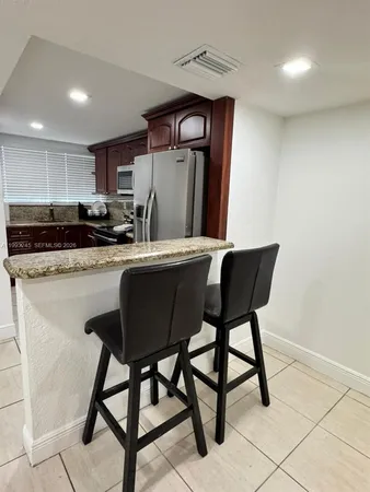 a kitchen with stainless steel appliances granite countertop a table chairs sink and cabinets
