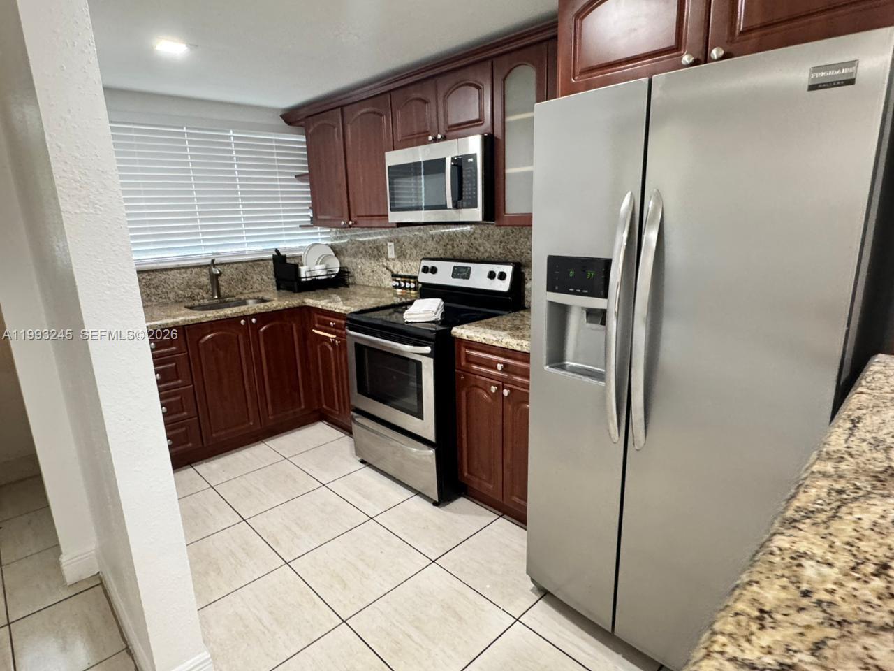 1910 Southwest 17th Avenue, Unit 4 Miami, FL 33145 - Photo 7 of 19 a kitchen with stainless steel appliances granite countertop a refrigerator stove and a sink