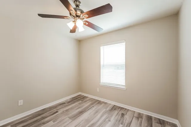 an empty room with a window and a fan