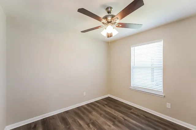 an empty room with windows and fan