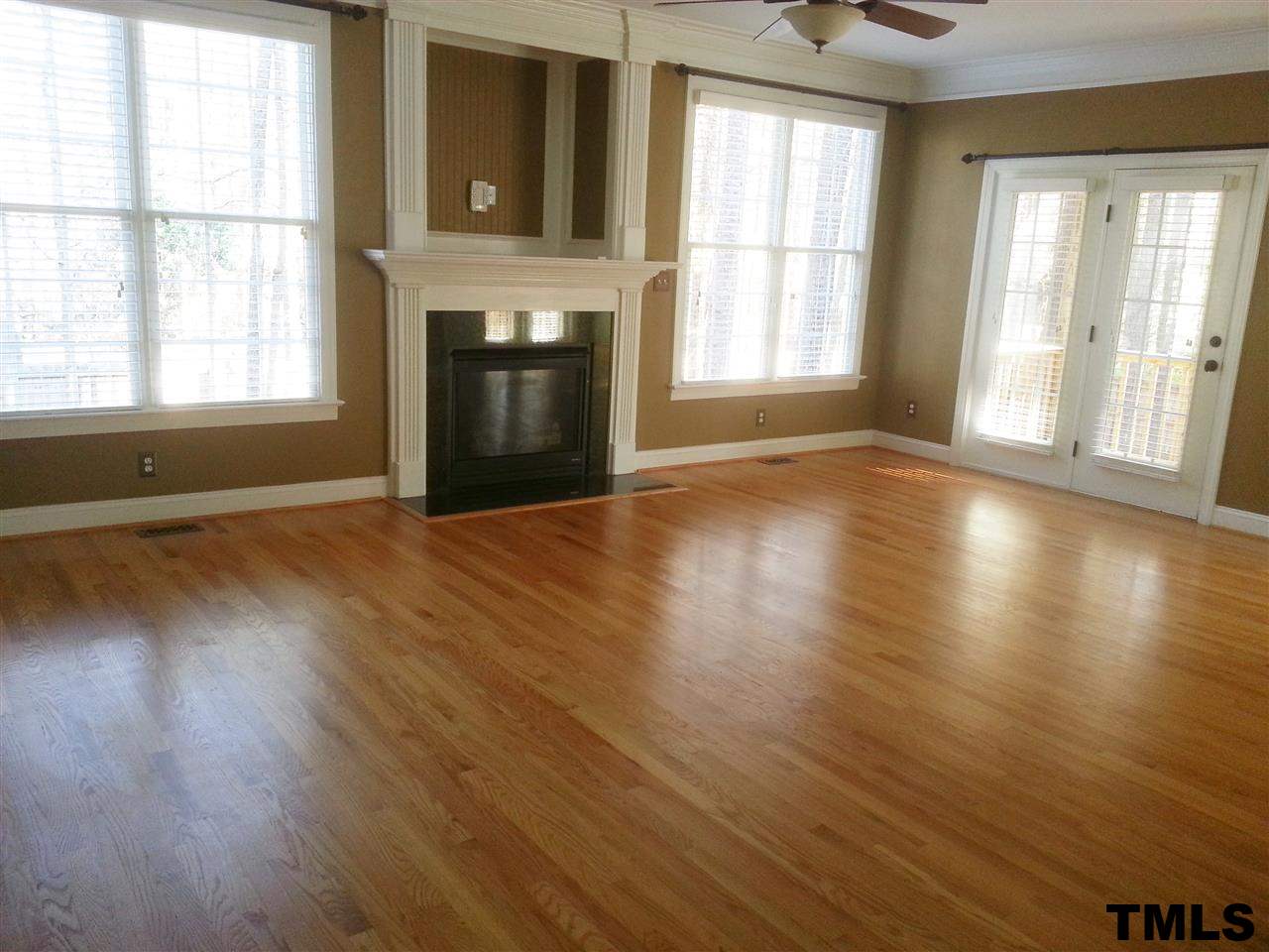 7203 Newport Avenue Raleigh, NC 27613 - Photo 3 of 24 an empty room with wooden floor fireplace and windows