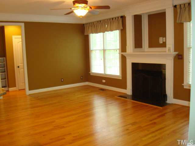 7203 Newport Avenue Raleigh, NC 27613 - Photo 4 of 24 an empty room with a fireplace and windows