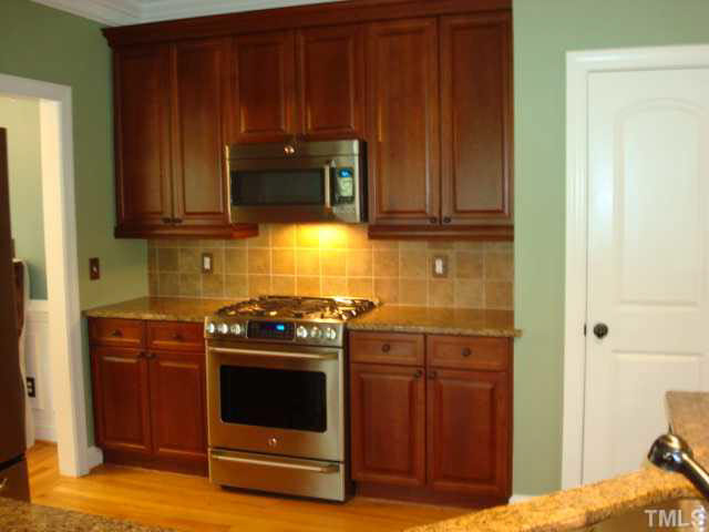 7203 Newport Avenue Raleigh, NC 27613 - Photo 6 of 24 a kitchen with wooden cabinets and a stove top oven