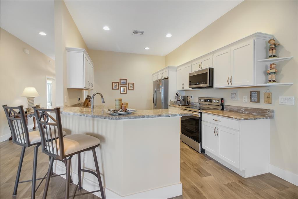 3323 Rohan Road Oxford, FL 34484 - Photo 12 of 46 a kitchen with kitchen island granite countertop wooden cabinets and stainless steel appliances