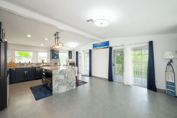 a large living room with stainless steel appliances kitchen island granite countertop furniture and a kitchen view