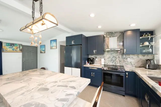 a kitchen with stainless steel appliances kitchen island granite countertop a sink a stove a refrigerator cabinets and a dining table