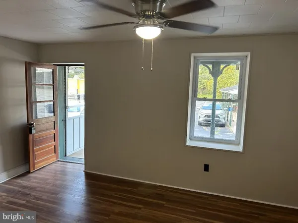 a view of an empty room with a window and wooden floor
