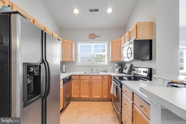 a kitchen with stainless steel appliances granite countertop a refrigerator a sink a stove a microwave a counter space and cabinets
