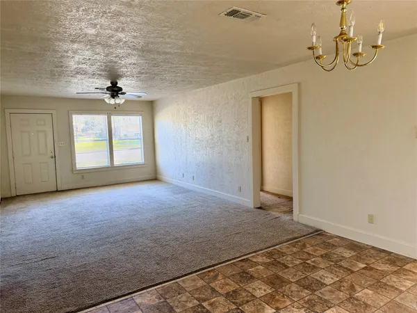 an empty room with windows and chandelier fan