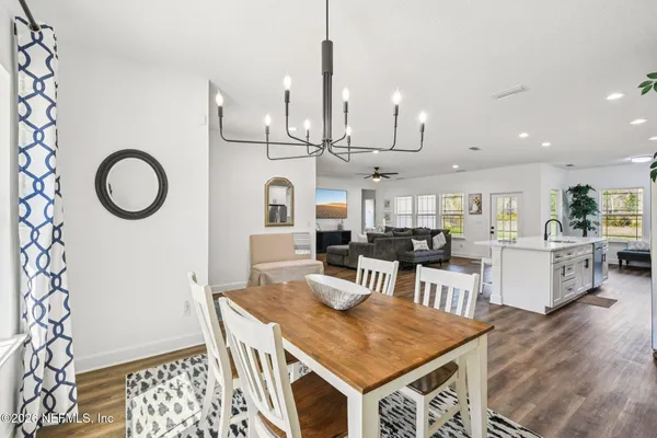 a kitchen with kitchen island granite countertop a refrigerator a stove a sink a dining table and chairs with wooden floor