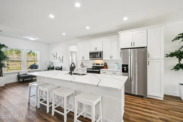 a large white kitchen with a lot of counter space and a wooden floor