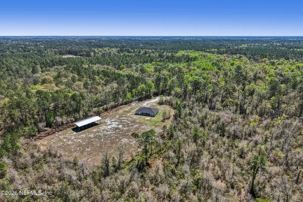 an aerial view of residential houses with outdoor space and trees