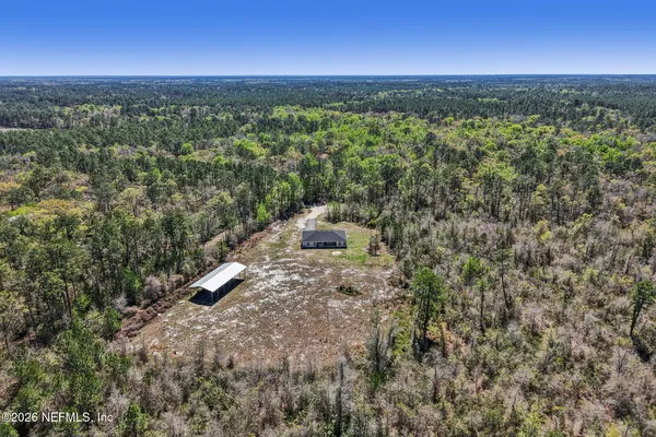 an aerial view of residential houses with outdoor space and trees