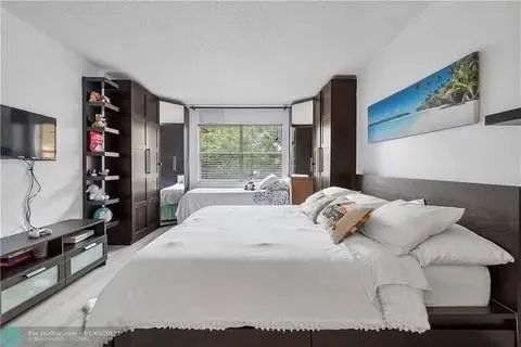 a bedroom with a large bed and a flat tv screen on dresser