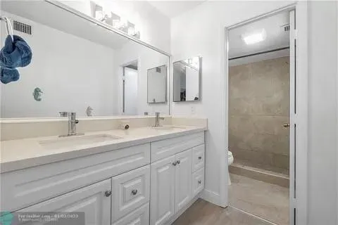 a bathroom with a double vanity sink mirror and shower