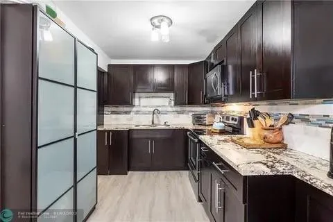 a kitchen with kitchen island granite countertop a sink stainless steel appliances and cabinets