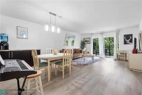 a dining room with wooden floor a chandelier a wooden table and chairs