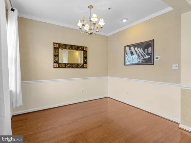 en empty room with a chandelier fan and wooden floor
