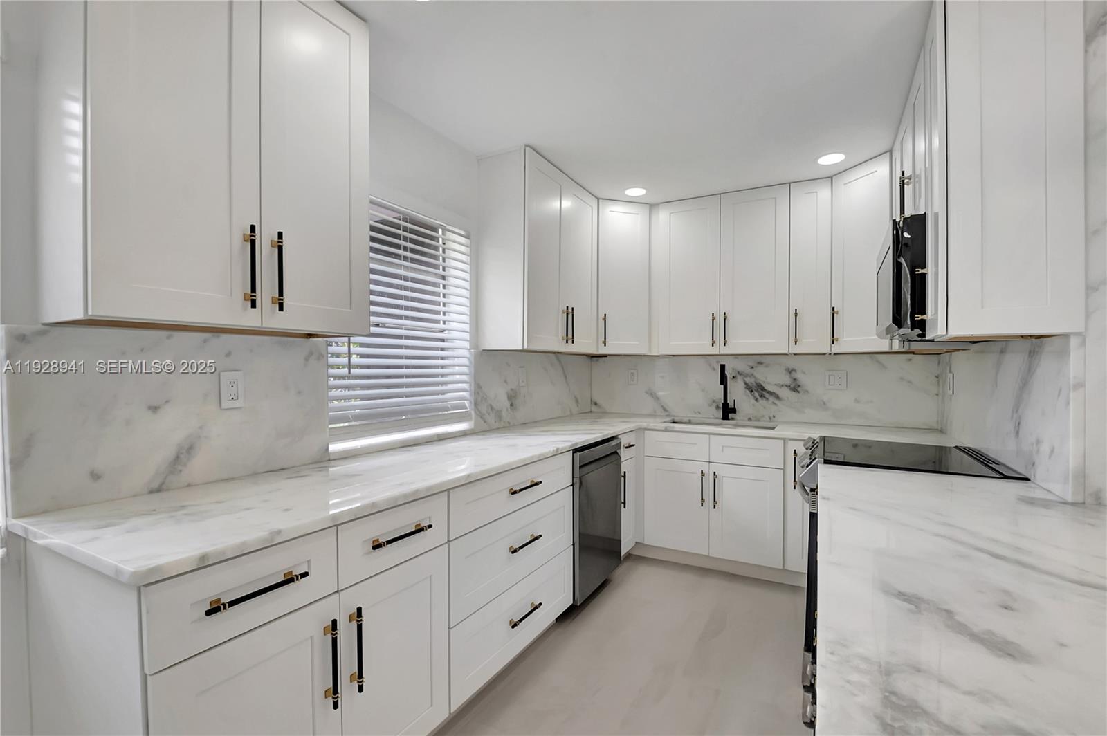 708 Normandy Lane, Unit 708 Delray Beach, FL 33484 - Photo 5 of 43 a kitchen with granite countertop white cabinets and white appliances