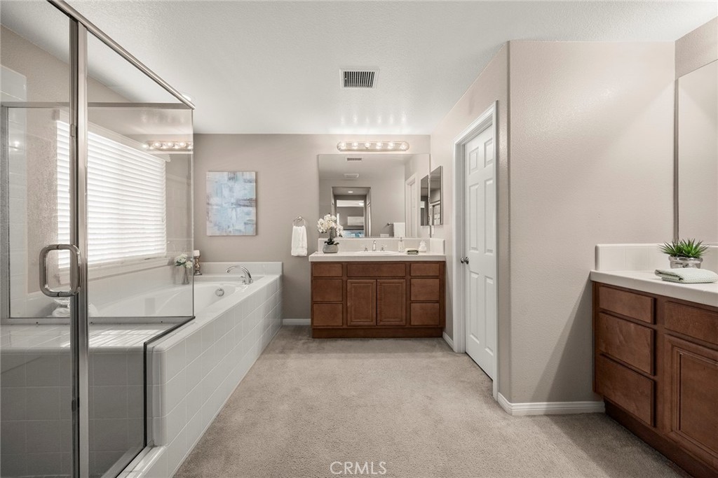 14280 Brant Court Eastvale, CA 92880 - Photo 36 of 47 a bathroom with a double vanity sink a large mirror and a bathtub