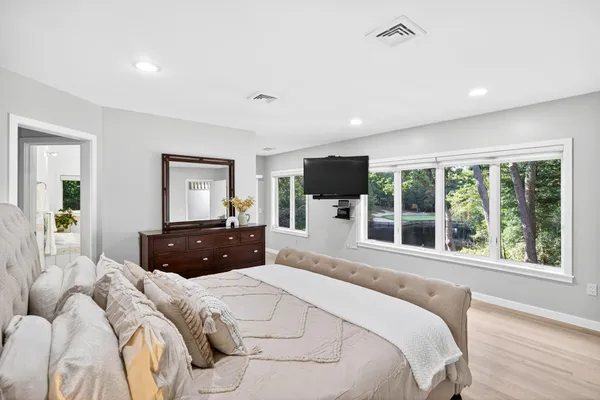 a bedroom with a large bed and a flat tv screen on dresser