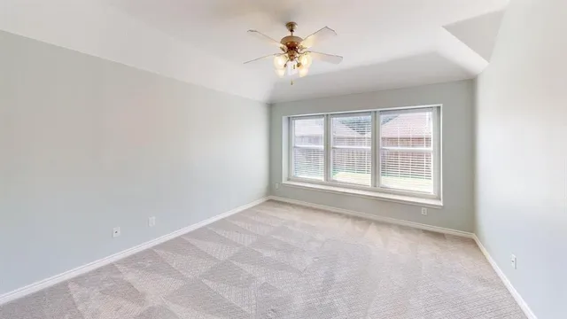 an empty room with a chandelier fan and windows
