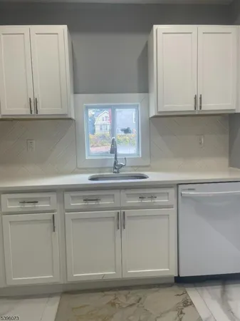 a kitchen with granite countertop white cabinets and a sink