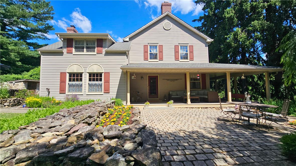 585 Buttermilk Road Hellertown, PA 18055 - Photo 2 of 82 A charming residence welcomes with an inviting covered porch and a stone-lined garden.