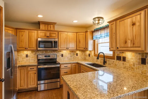 a kitchen with stainless steel appliances granite countertop a sink a stove and a microwave