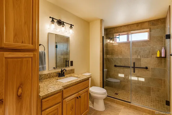 a bathroom with a granite countertop sink toilet and shower