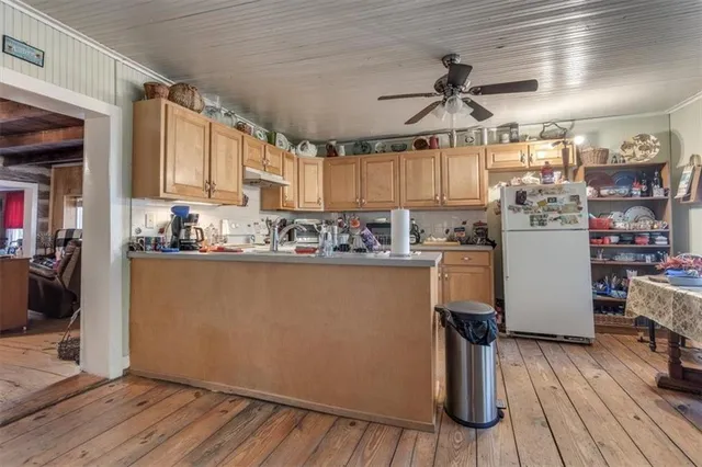 a kitchen with stainless steel appliances granite countertop a stove top oven a refrigerator a sink dishwasher and wooden cabinets with wooden floor