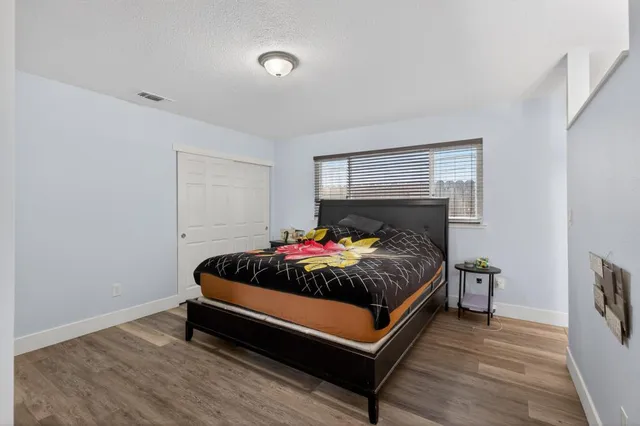 a bed sitting in a bedroom next to a lamp with wooden floor