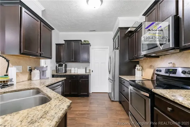 a kitchen with granite countertop a sink stove and refrigerator