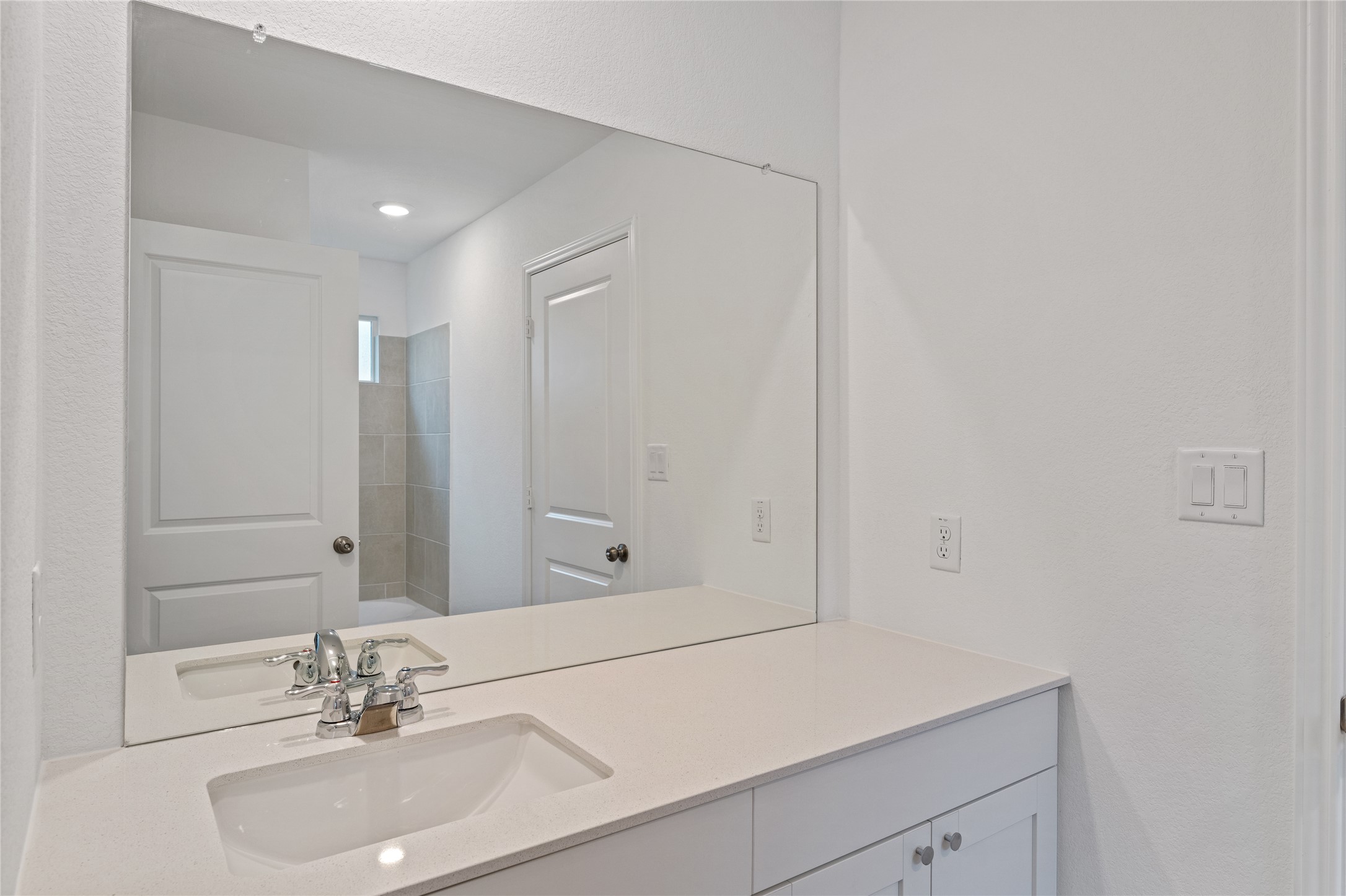 115 Parsons Kyle, TX 78640 - Photo 10 of 18 Reflective surfaces create an airy feel, complemented by pristine white cabinetry and a practical vanity.