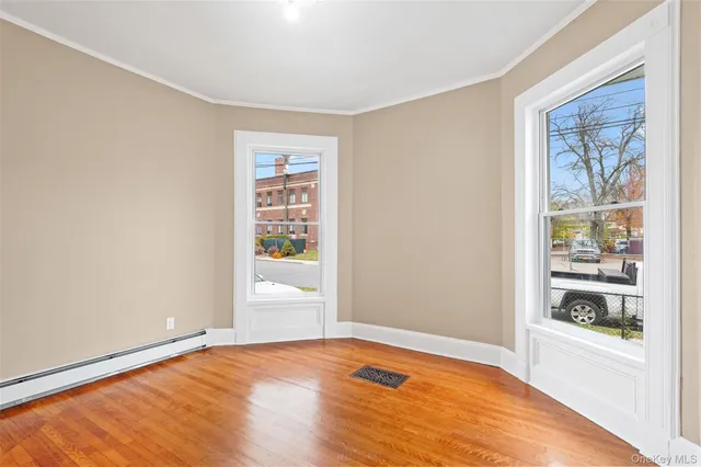 a view of an empty room with wooden floor and a window
