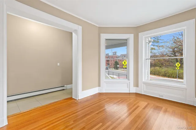 a view of an empty room with wooden floor and a window