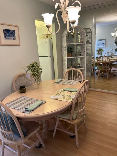 1955 Southwest Palm City Road, Unit H Stuart, FL 34994 - Photo 13 of 22 a dining room with furniture a chandelier and wooden floor