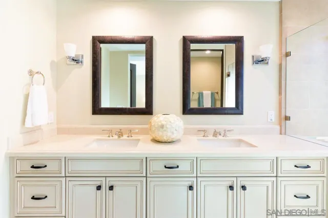 a bathroom with double vanity sink and two mirror