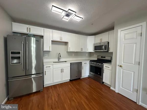 a kitchen with a refrigerator a stove top oven and wooden floor