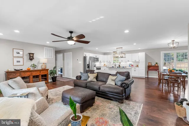 a living room with furniture kitchen view and a chandelier