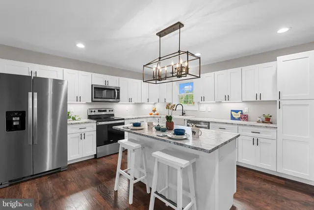 a kitchen with stainless steel appliances granite countertop a stove a sink dishwasher a refrigerator white cabinets with wooden floor