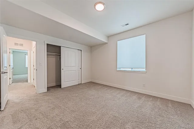 an empty room with closet area and windows