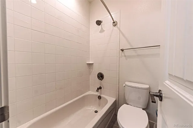a white toilet sitting next to a bath tub and a shower