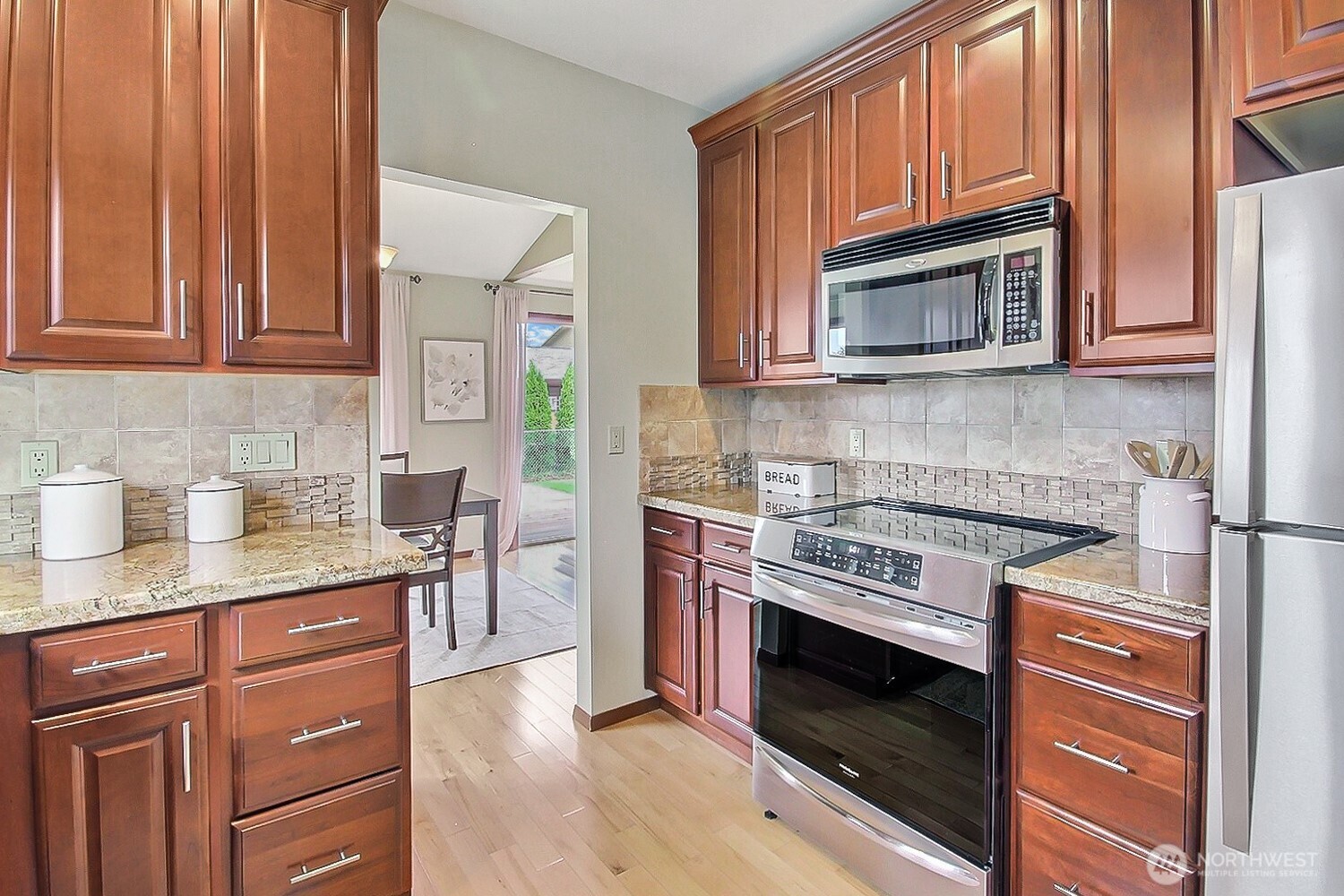 21834 Southeast 265th Way Maple Valley, WA 98038 - Photo 9 of 31 a kitchen with granite countertop a stove top oven microwave and cabinets