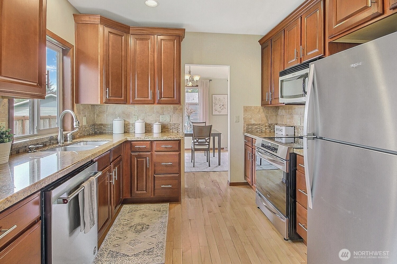 21834 Southeast 265th Way Maple Valley, WA 98038 - Photo 10 of 31 a kitchen with stainless steel appliances granite countertop a refrigerator a sink dishwasher a stove with wooden cabinets and floor
