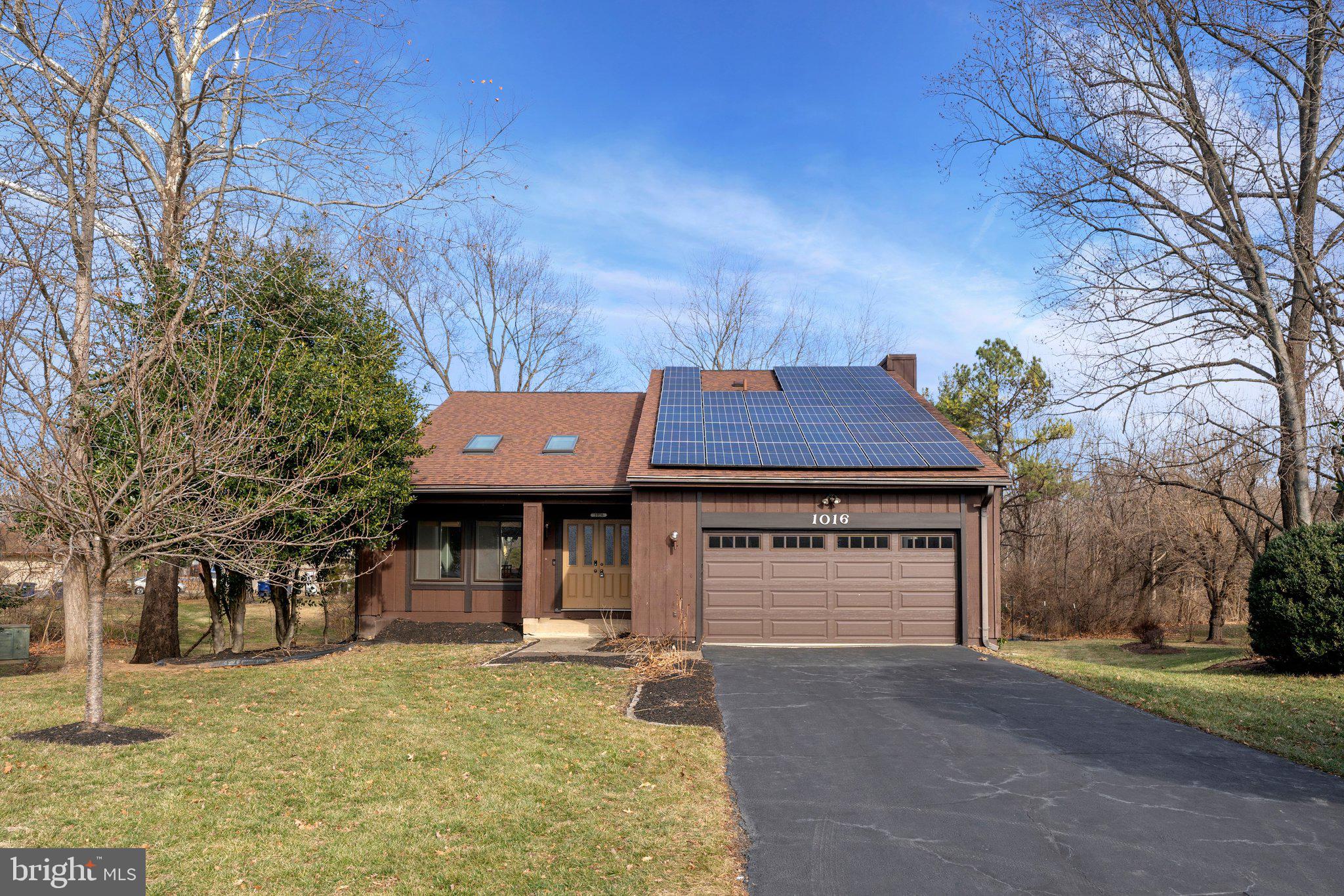 a front view of a house with a garden and tree