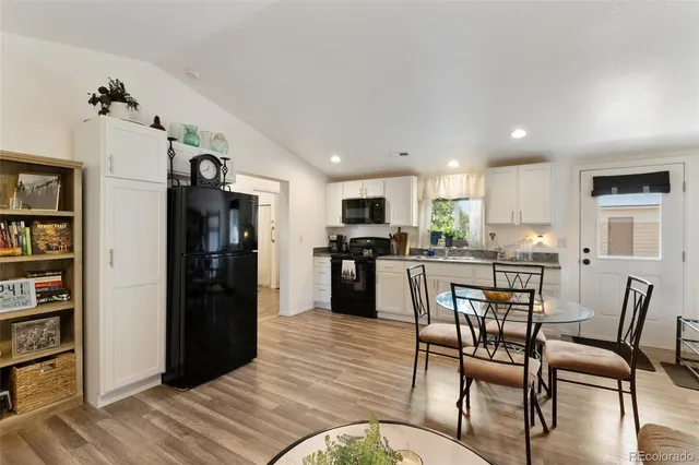 a kitchen with stainless steel appliances kitchen island granite countertop a refrigerator a stove a microwave oven a dining table and chairs with wooden floor