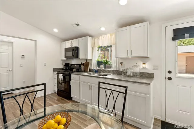 a kitchen with granite countertop a stove a sink and a refrigerator