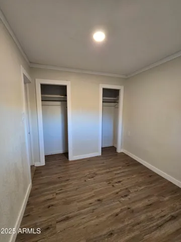 a view of an empty room with wooden floor and closet